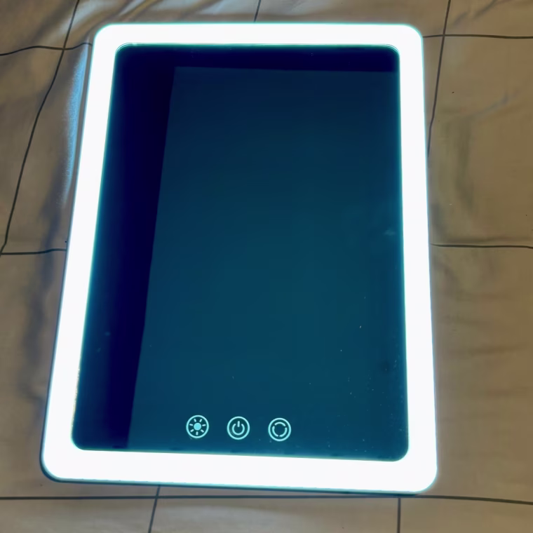 LED rectangular mirror lying on a bed