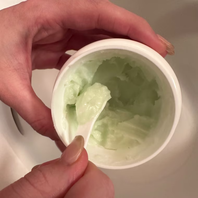 Woman scooping out cleansing balm from tub