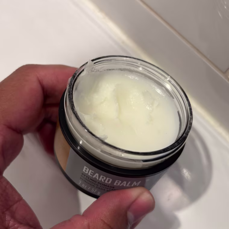 Man holding option container of Manscaped beard pomade.