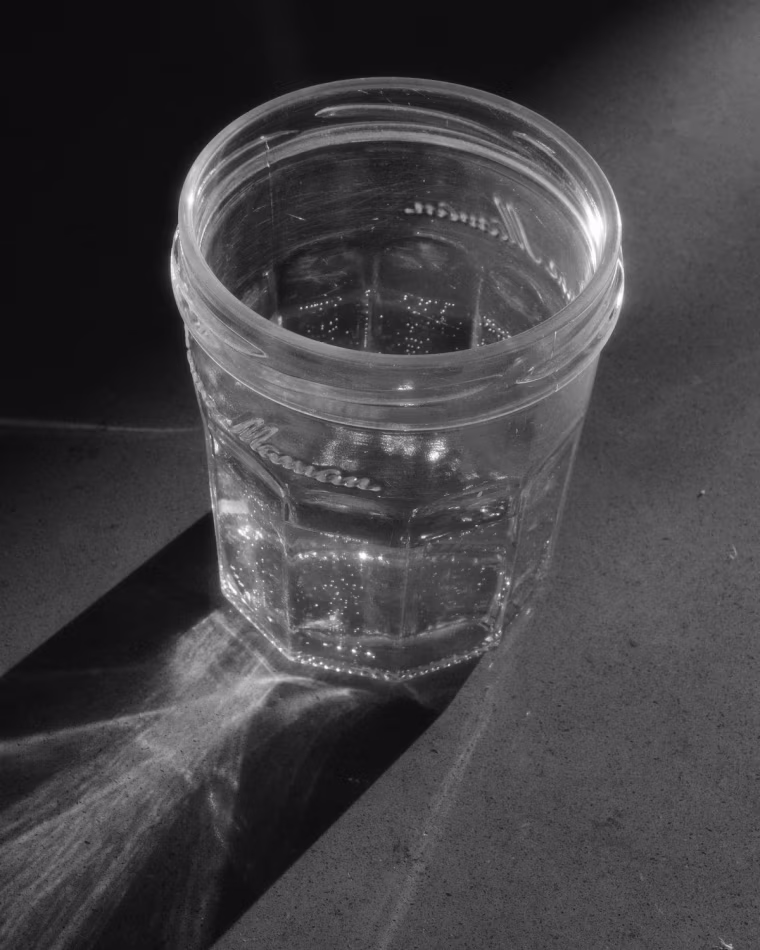 A close up of sparkling water in an old-fashioned mason jar glass, photographed in black and white.
