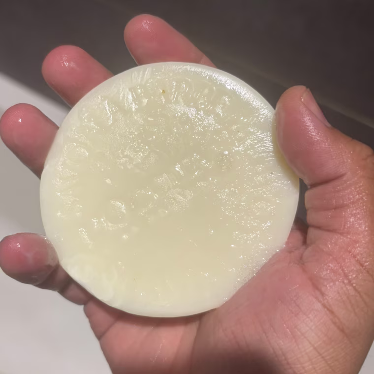 Person holding L’occitane shave bar in hand in the shower.