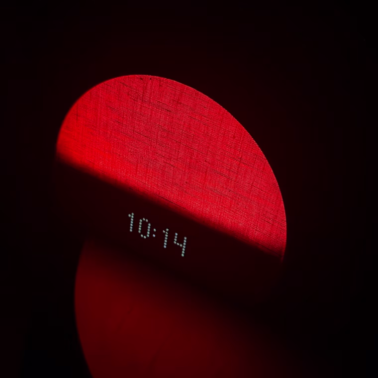 Hatch Restore 2 sitting on a bedside table in the dark with a red light.
