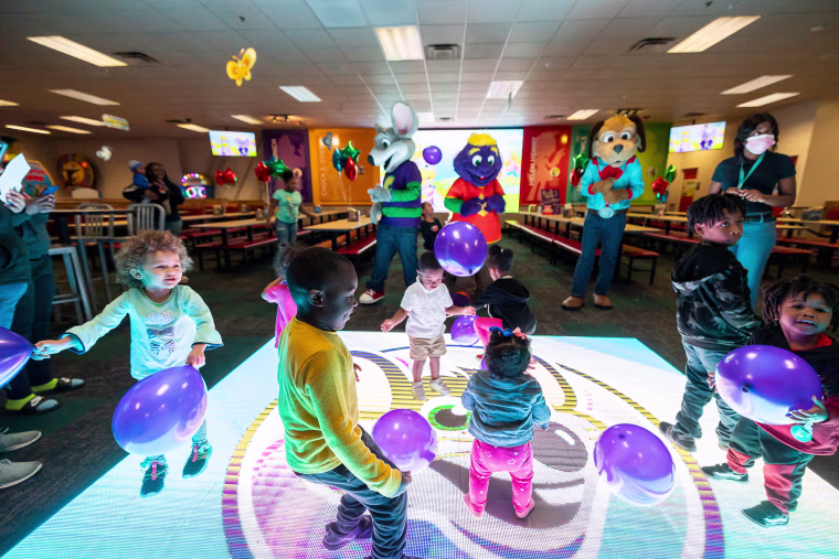 Children dance on a dancefloor with a screen beneath it