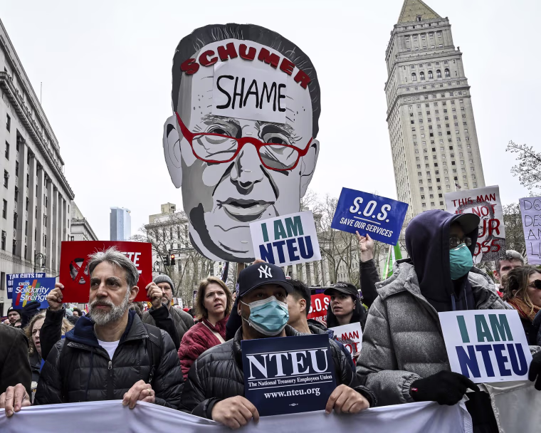 A demonstrator holds up a cutout of Sen. Chuck Schumer