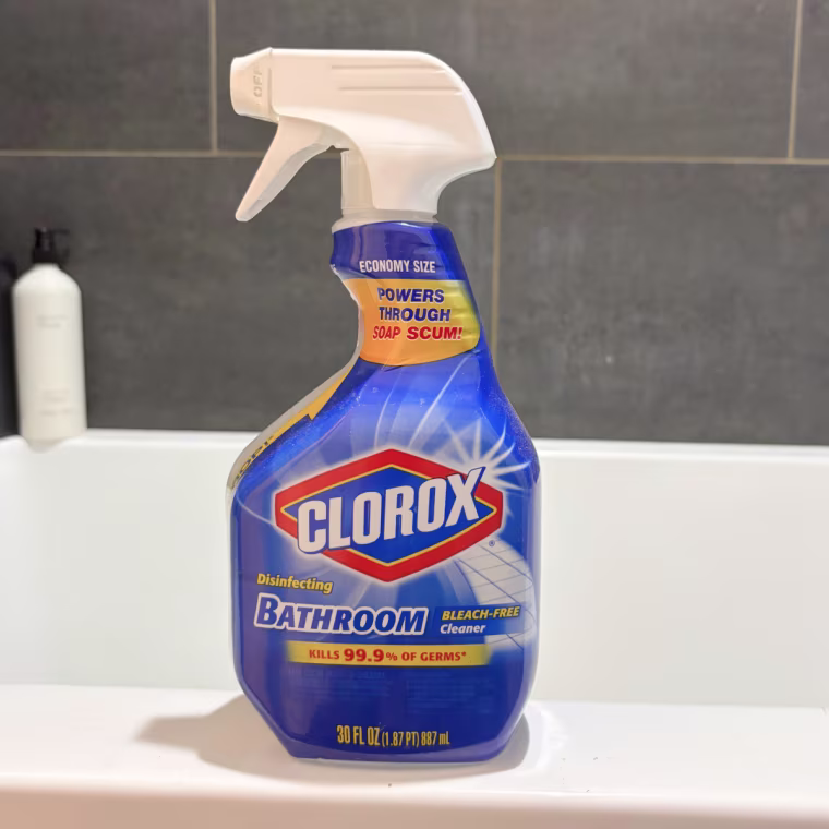 Spray bottle of Clorox disinfectant spray sitting on the side of the bathtub.