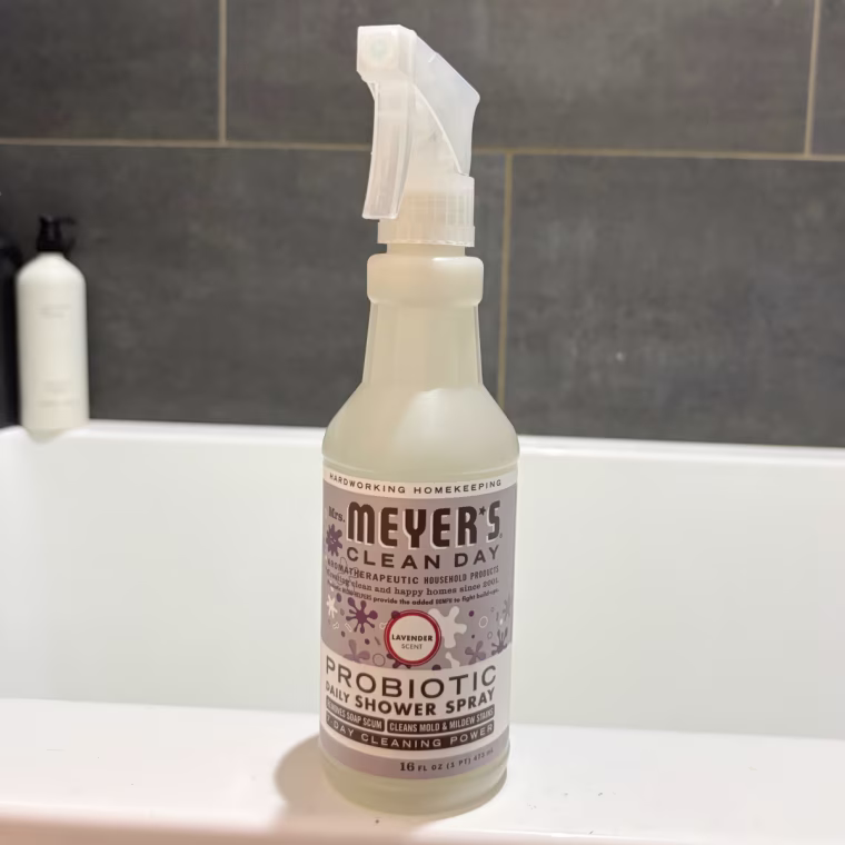 Mrs. Meyers Probiotic Shower Spray sitting on the side of a bathtub.