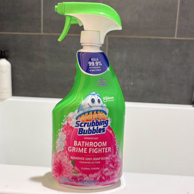 Scrubbing Bubbles shower cleaner spray sitting on the side of a bathtub.