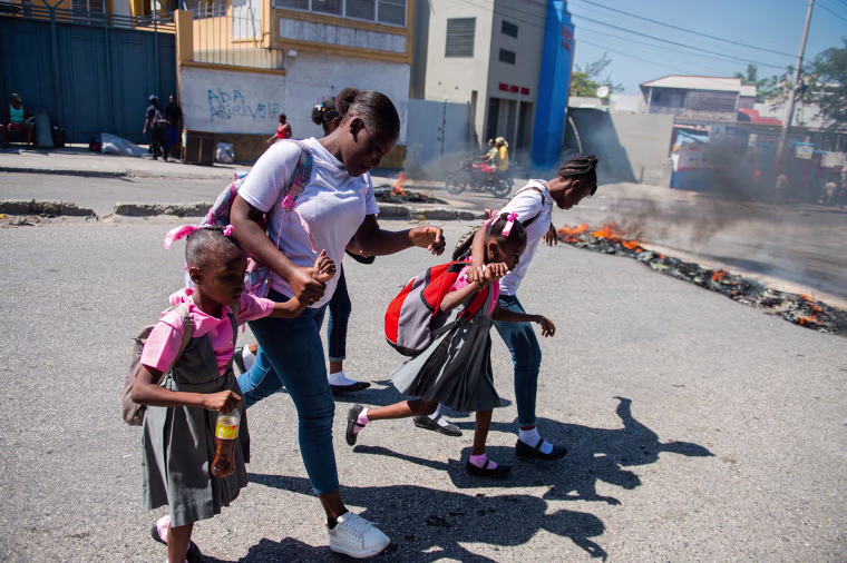 People flee gang violence during an anti-government demonstration in of Port-au-Prince, Haiti, on Feb. 20, 2025.