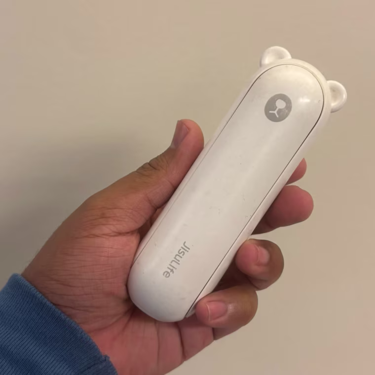 Jisulife handheld fan lying on its side on a table.