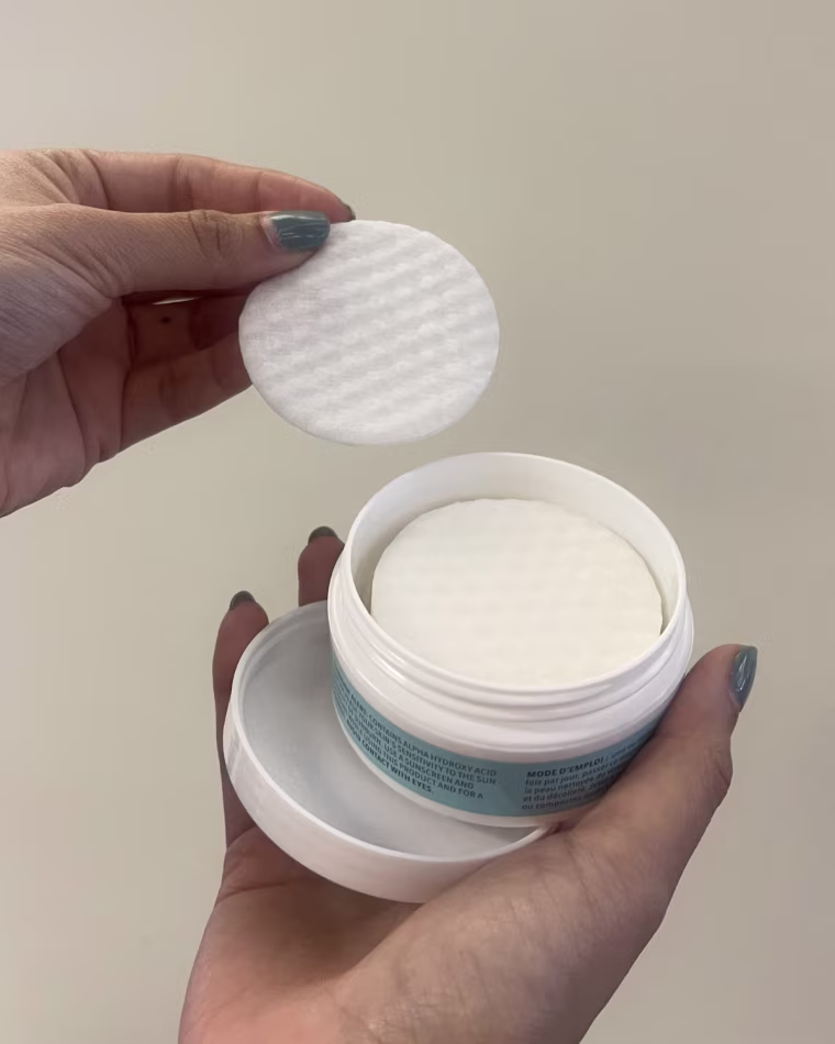 Woman removes one of the Facial Radiance Pads from the jar it comes in and holds it in her hand.