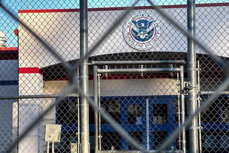 A detention facility is seen behind a chainlink fence