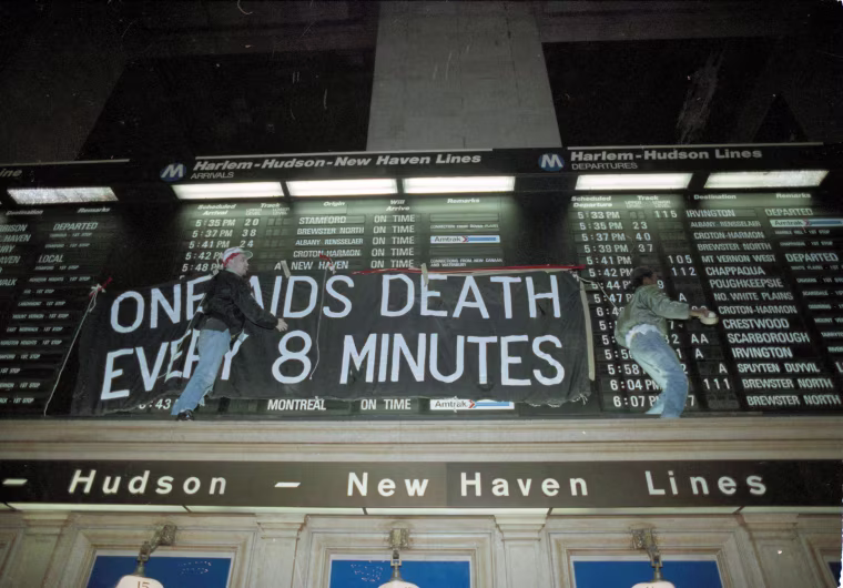 Members of the AIDS activist group ACT-UP hang a banner across the train schedule board in New York's Grand Central Terminal on Jan. 24, 1991.