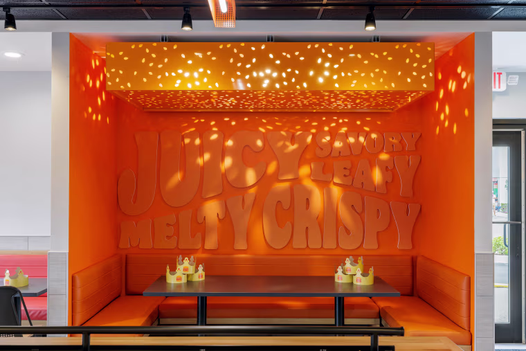 Juicy, Savory, Leafy, Melty and Crispy embossed in a giant orange booth.