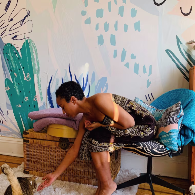 Woman in chair in front of Coloray wallpaper.