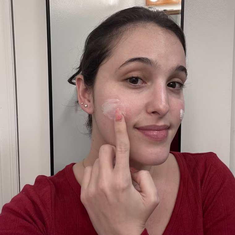 Woman applying sunscreen to cheek.