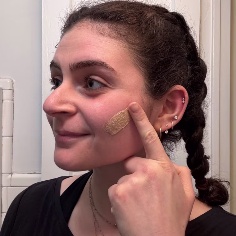 Woman swatches Naturium Dew-Glow Moisturizer on her cheek.