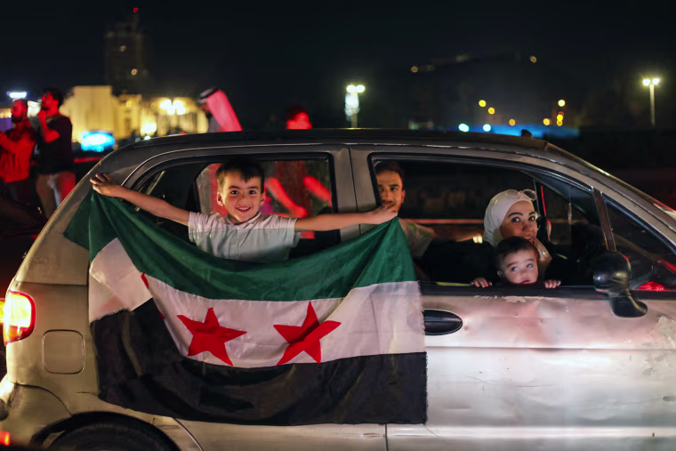 A young boy holds a Syria flag from a car in Damascus' Omeyyad square