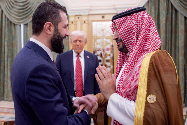 Saudi Crown Prince Mohammed bin Salman shakes hands with Syria's interim president Ahmed al-Sharaa as US President Donald Trump looks on.