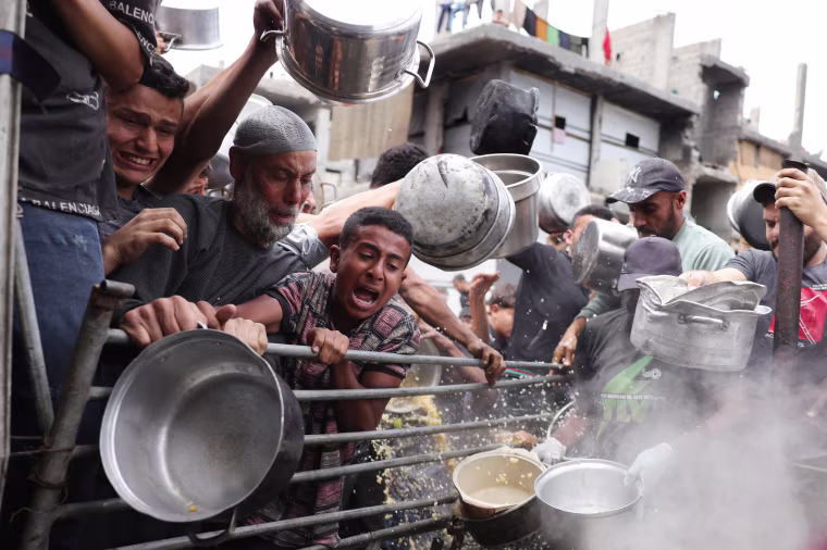 Palestinians struggle to get their food rations ouside a crowded distribution centre