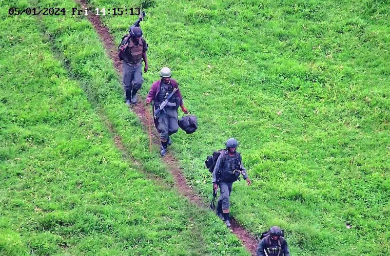 Rwandan soldiers walk across a field.