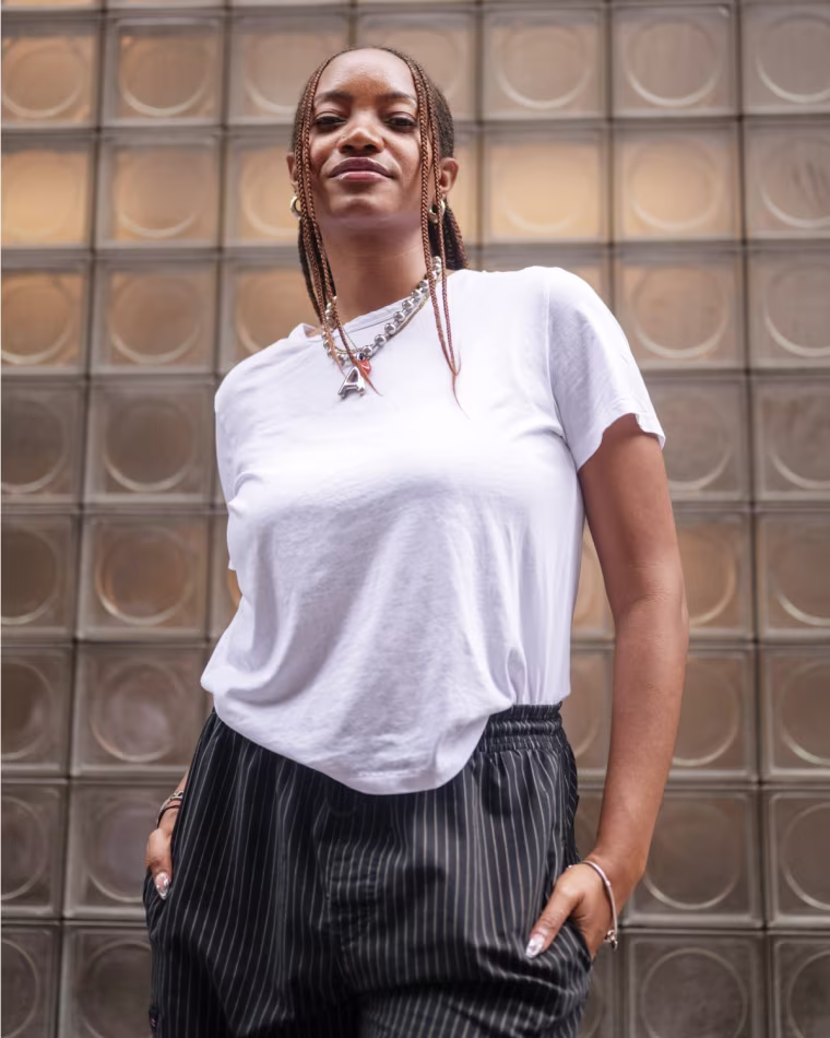 An NBC Select editor modeling a white t-shirt against a frosted glass exterior.