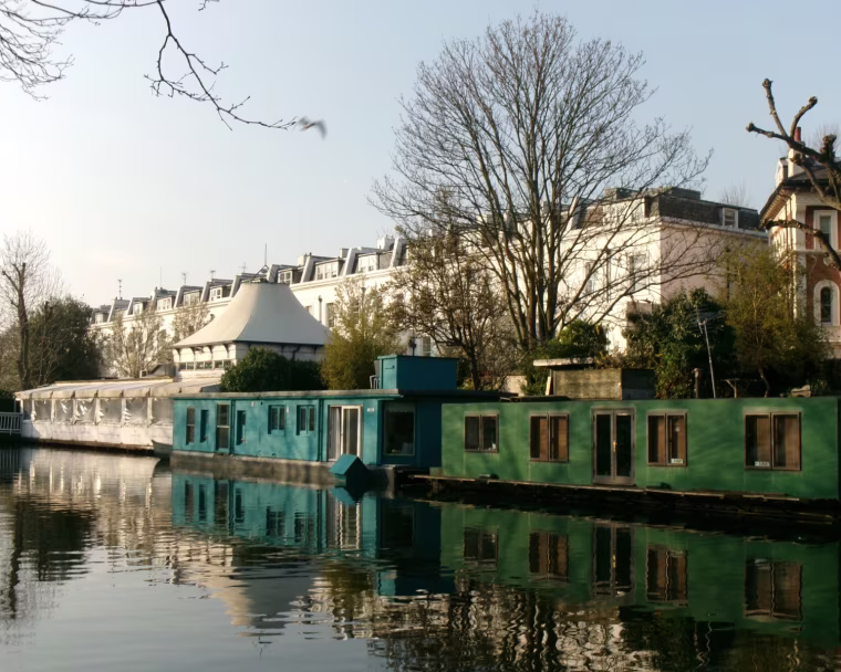 A photo of green and red houses along a river in a city.