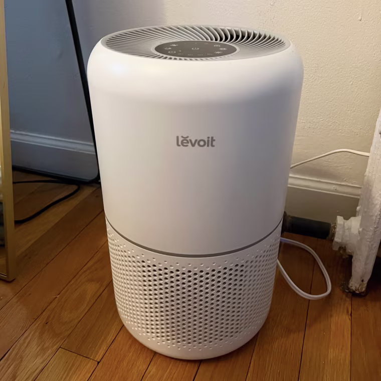 A photo of the Levoit Core 300 air purifier plugged into the corner of a room.