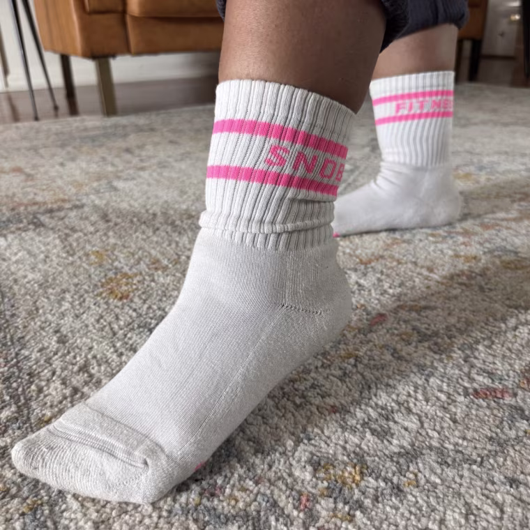 A woman wearing a pair of FitnessSnob Not Your Basic Crew socks without shoes on.