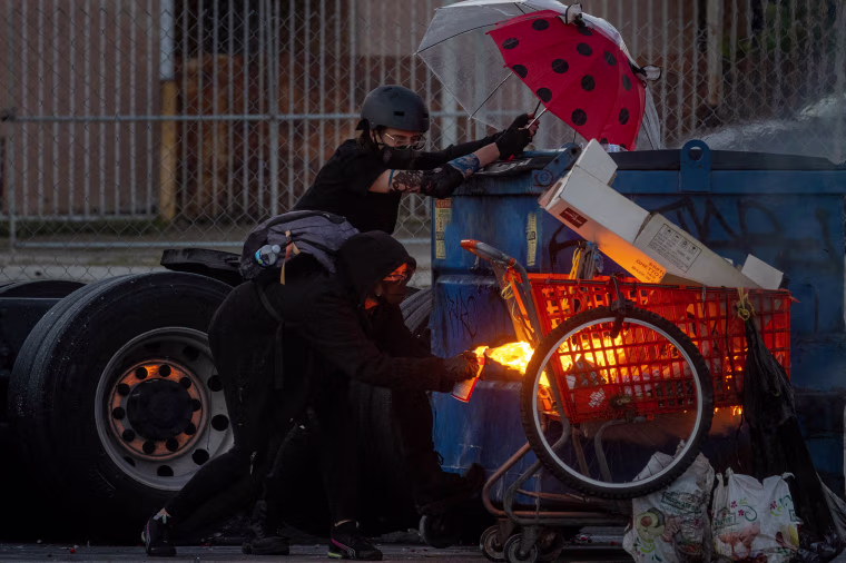 A protester sets fire to a shopping cart during a standoff with law enforcement in Compton