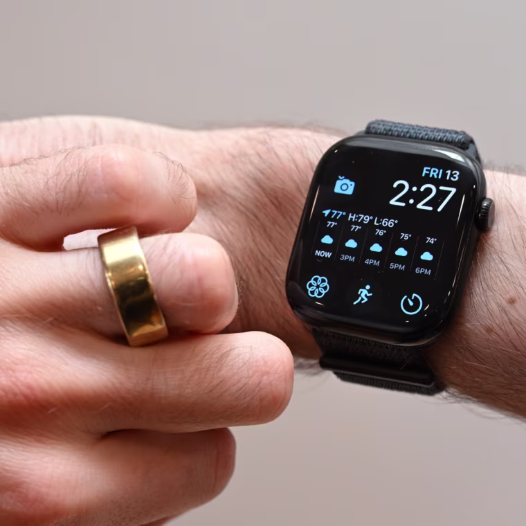 A close-up of the writer’s left hand and right wrist. One has a gold Oura Ring on it, the other is wearing an Apple Watch Series 10.
