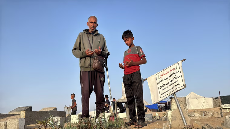 Ahmed Darwish, left, prays at a cemetery in Khan Younis on Friday.