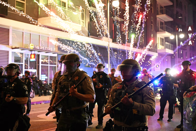 Fireworks explode behind Ventura County Sheriff's department deputies in riot gear 