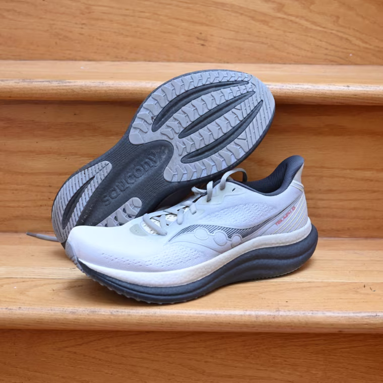 A close up of the Saucony Triumph 23 shoes. One shoe is propped to show the bottom tread.