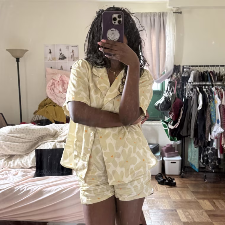 Photo of woman taking a mirror selfie in yellow, floral print pajamas.
