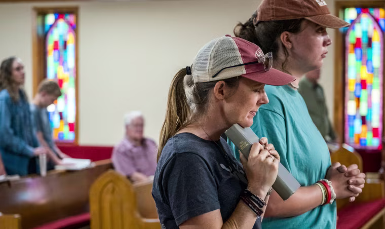 Ginger Turner and Hailey Turner pray inside of a church