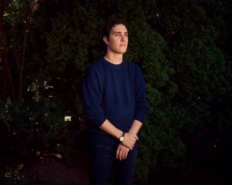Kevin Keystone stands outside in front of a tall bush
