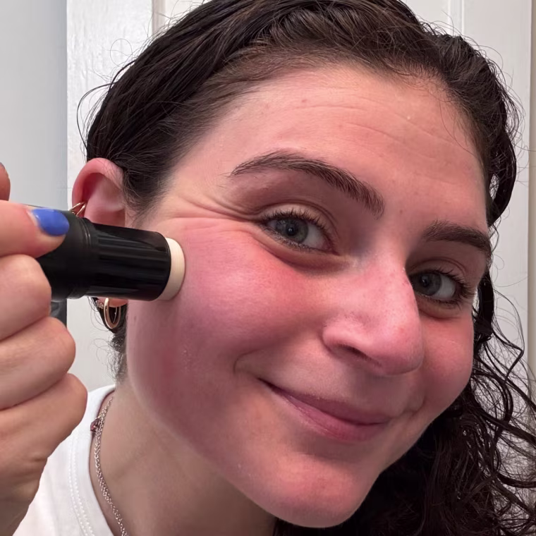 Woman applying Milk Makeup stick primer to her cheek