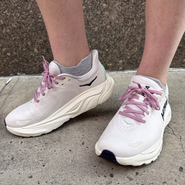 A woman wearing a lavender pair of Hoka Arahi 8 sneakers.