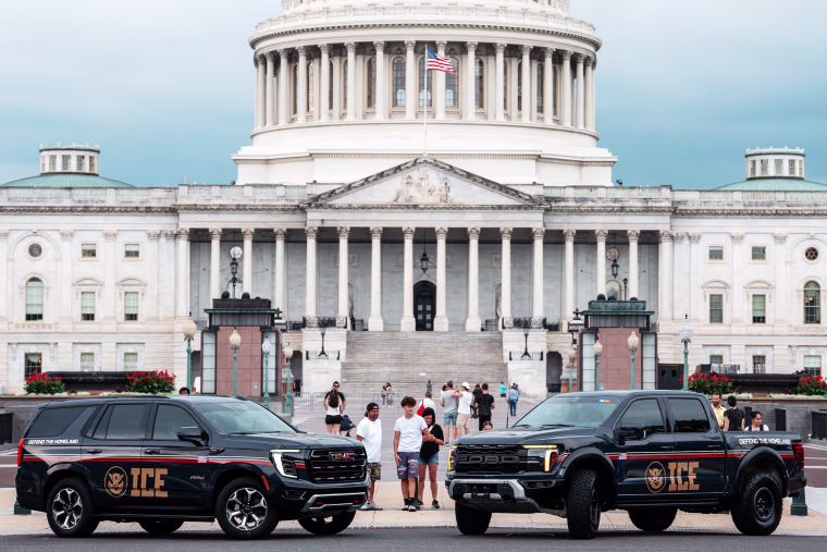 People look at An Immigration and Customs Enforcement (ICE) branded GMC SUV and an Immigration and Customs Enforcement (ICE) branded Ford pickup truck parked at the Capitol