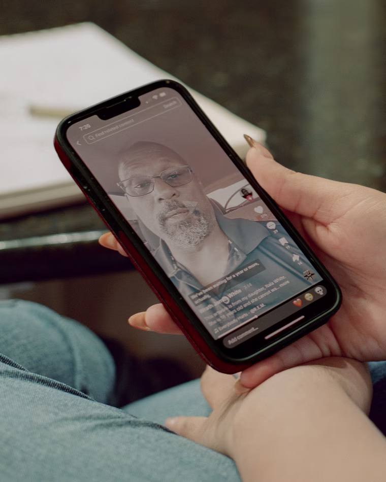 A hand holds a phone showing a video of Wrath James White