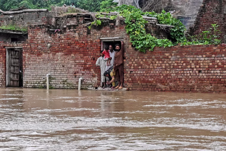 Villagers stand inside their house partially submerged with floodwaters