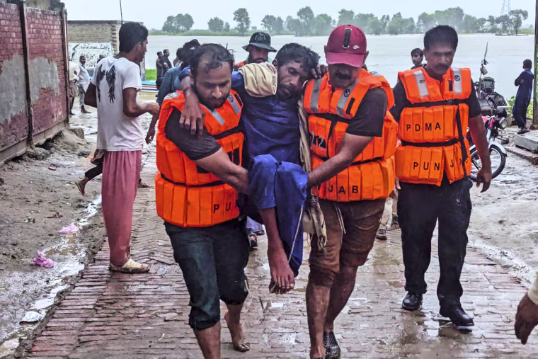 Rescue workers wearing life jackets carry a villager after evacuating him