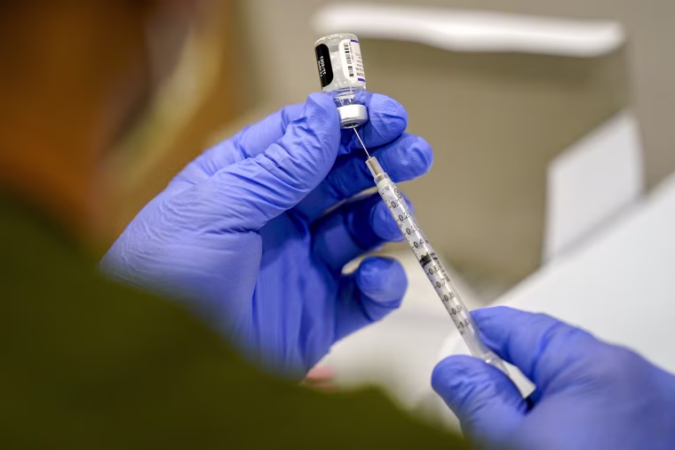 A healthcare worker fills a syringe.