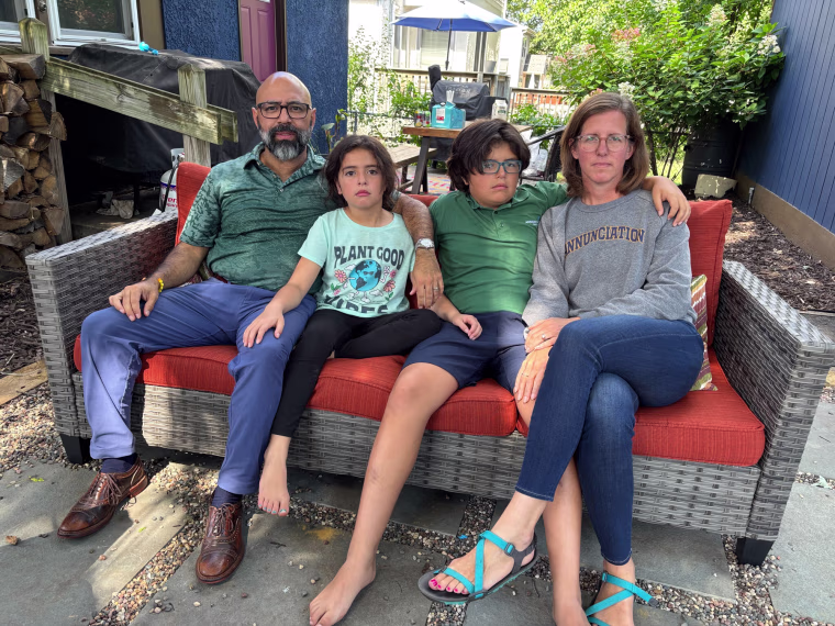 From left, from left, Pedro, Pilar, Pablo, and Carla sit on a couch outside with a dog.