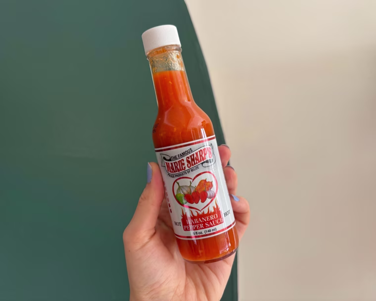 A hand holding a bottle of Marie Sharp’s Original Hot Habanero Pepper Sauce.