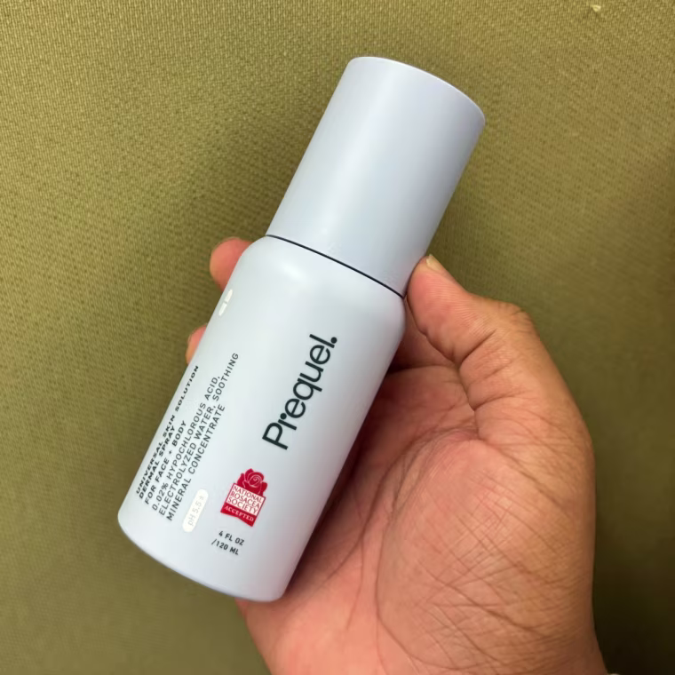 Person holding Prequel Universal Skin Solution Dermal Spray in hand.