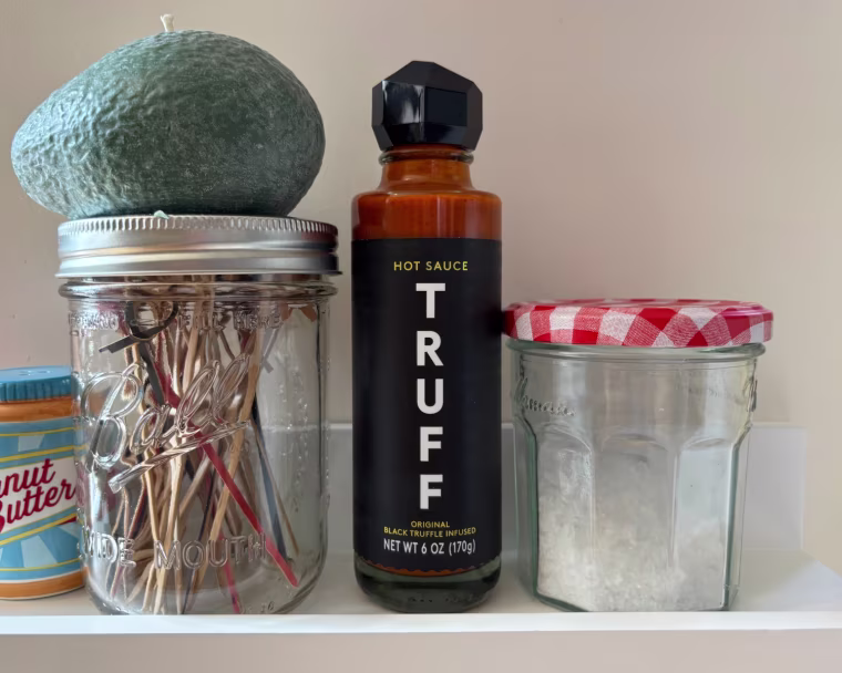 A bottle of Truff Original Black Truffle Hot Sauce on a shelf.