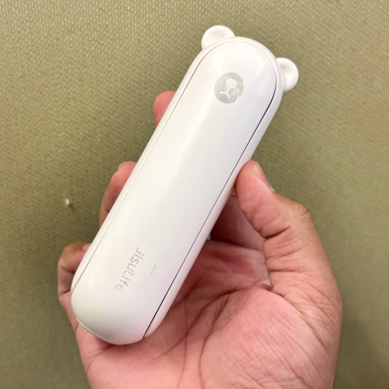 Person holding white Jisulife handheld fan in right hand.