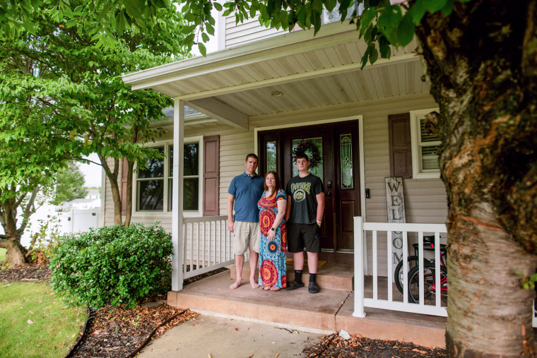Nick, Misty, and Jonathan stand on the porch of their home outside