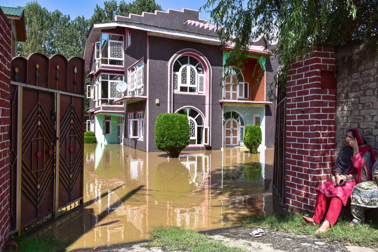 A Kashmiri woman sits outside her partially submerged house